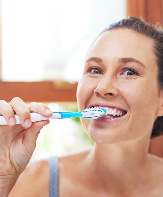 Woman brushing her teeth to prevent a dental emergency in Charleston