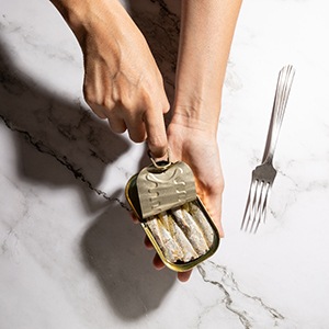 Person opening a container with their finger and fork