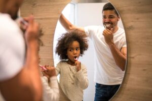 Father and daughter brushing their teeth in bathroom 